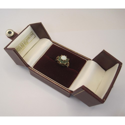 164 - A 9 carat gold ring with central opal surrounded by 8 emeralds, approx weight 3.1g