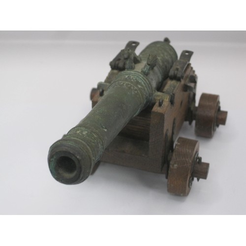 177 - An ornate bronze model of a cannon on an oak carriage