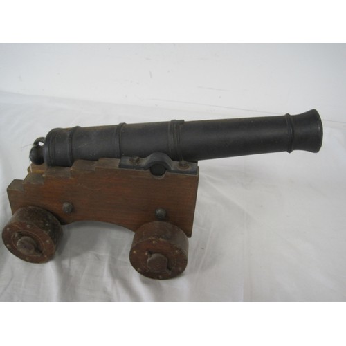 10 - A cast iron signal cannon on a wooden carriage with wooden wheels. The barrel having a length of 40c... 