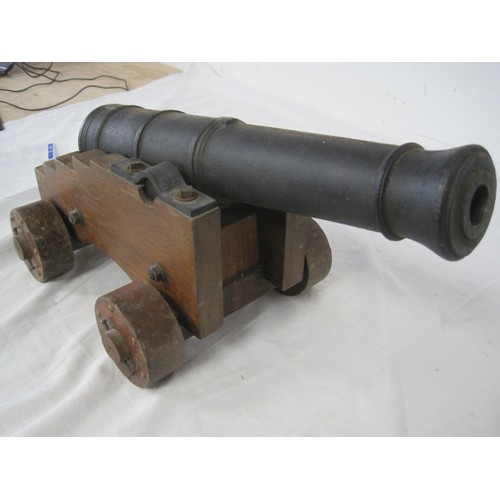 10 - A cast iron signal cannon on a wooden carriage with wooden wheels. The barrel having a length of 40c... 