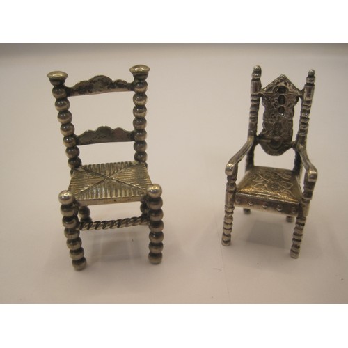 214 - Two foreign silver miniature chairs. (1) ladderback, height 4cm, indistinct stamped marks, 13.9g. (2... 