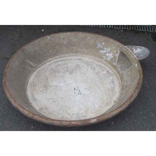 10 - A large metal mixing bowl probably for cement with a pouring spout .