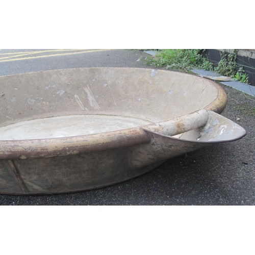 10 - A large metal mixing bowl probably for cement with a pouring spout .