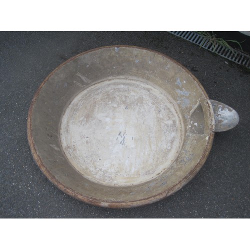 10 - A large metal mixing bowl probably for cement with a pouring spout .