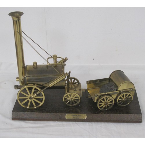 36 - A brass model of Stephenson's Rocket mounted on a wooden plinth and a tin plate model of a John Deer... 