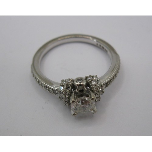 228 - An 18 carat white gold solitaire diamond ring. The central stone estimated at 0.5 carat, with furthe... 