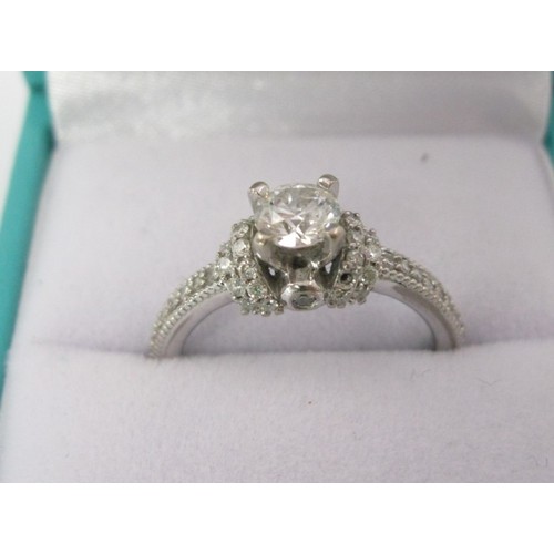 228 - An 18 carat white gold solitaire diamond ring. The central stone estimated at 0.5 carat, with furthe... 