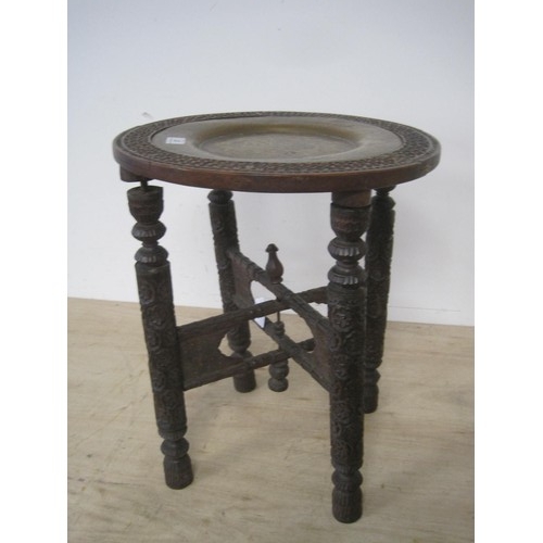 37 - A heavily carved Indian hardwood folding circular table with insert brass tray. 39.5cms diameter by ... 