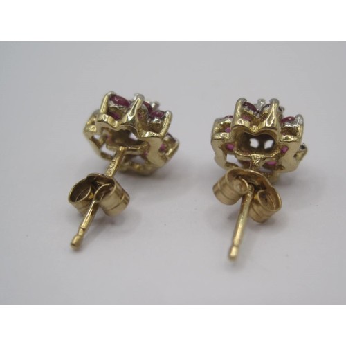 178 - A pair of 9 carat gold ruby and diamond earrings. Each earring set with a small central diamond surr... 