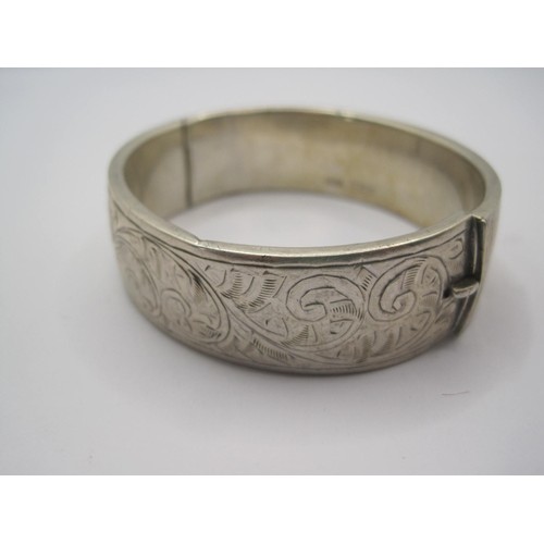 14 - A silver bangle (slight a/f some small dents), half-engraved with scrolled foliage, band width 18mm,... 