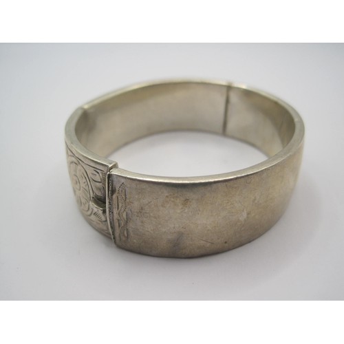 14 - A silver bangle (slight a/f some small dents), half-engraved with scrolled foliage, band width 18mm,... 