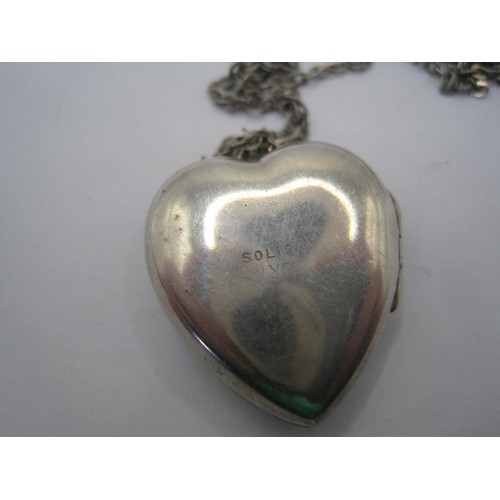 21 - A heart-shaped locket with foliate engraving to one side, stamped solid silver, with trace chain sta... 