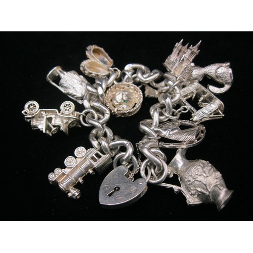 59 - A silver charm bracelet with padlock clasp, with 10 large charms in white metal, total approx weight... 