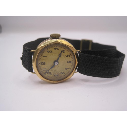 22 - A ladies mechanical wristwatch with yellow metal case and black fabric strap. The case is stamped wi... 