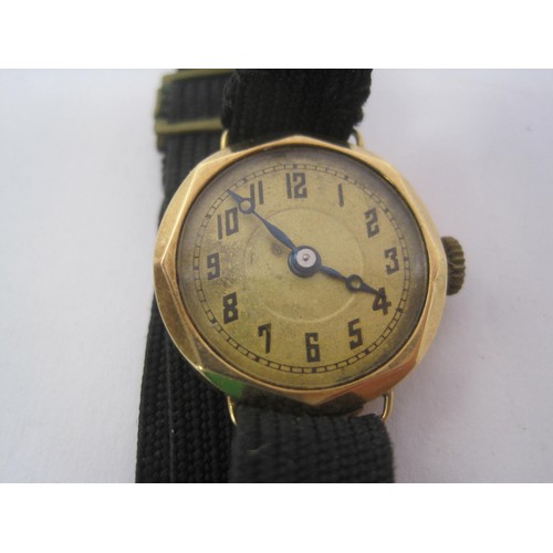 22 - A ladies mechanical wristwatch with yellow metal case and black fabric strap. The case is stamped wi... 