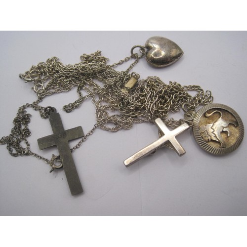 63 - A pair of silver crucifixes on chains, one with figural Christ, a silver heart shaped locket on a si... 