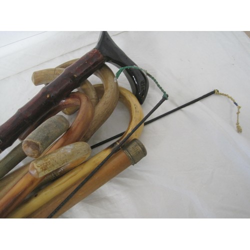 96 - A selection of Walking sticks ,two riding crops and a Tourist piece carved Bow all as per pictures