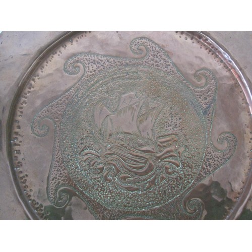 37 - A Newlyn style circular copper dish with embossed and hammered decoration of ship and stylized waves... 