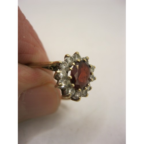 185 - A 9 carat gold ring with large central ruby surrounded by a cluster of 1 dozen small clear stones, v... 