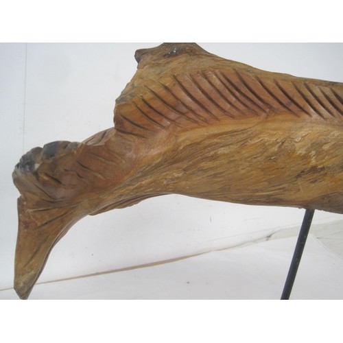 33 - A carved wooden figure of a spearfish or similar, raised on a metal pole and mounted on a rustic woo... 