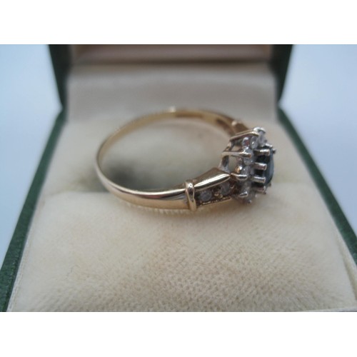 261 - A 9 carat imported gold ring set with a sapphire (estimated 5.5mm x 3.5mm) surrounded by small white... 