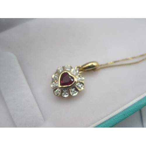 269 - A 9 carat imported gold heart-shape pendant on a fine gauge chain.  The pendant with a small ruby in... 