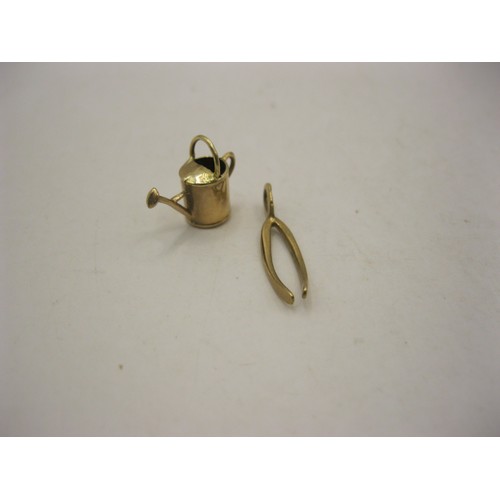 75 - Two 9 carat gold charms - a watering can (approx. 0.65g), and a wishbone (approx. 0.59g), both with ... 