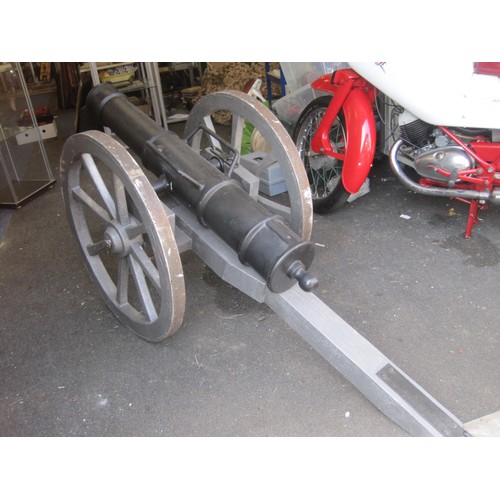 23C - A large cannon having a cast iron barrel mounted on a wooden carriage with metal fittings and 8 spok... 