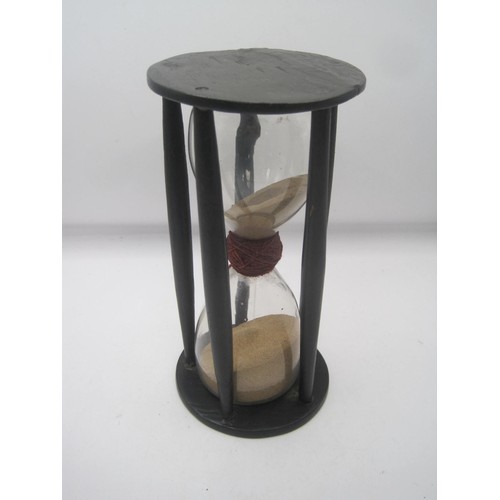 45 - A Victorian hand-blown hourglass in an ebony spindle frame. The glass is bound with red thread at th... 