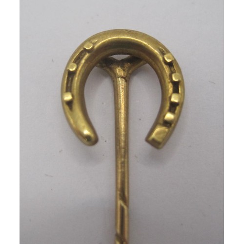 153 - A gold horseshoe stick pin, stamped 18CT, length about 56mm, approx. 1.7g. Acid test suggests 14 car... 