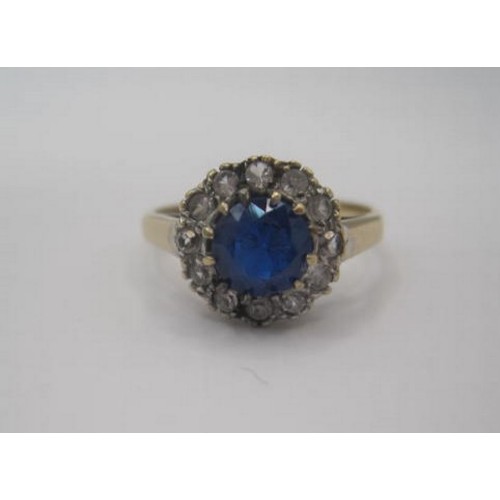 263 - A 9 carat gold dress ring set centrally with a round blue stone surrounded by twelve small white sto... 