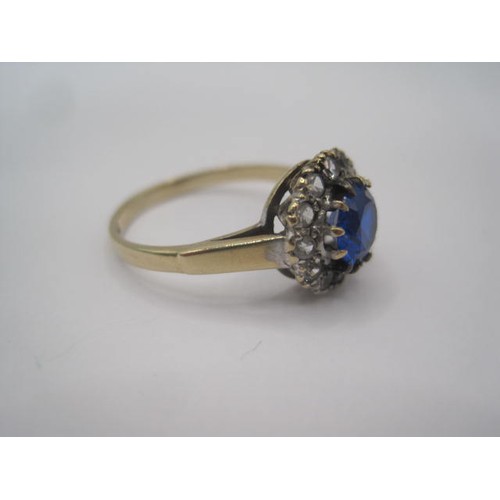 263 - A 9 carat gold dress ring set centrally with a round blue stone surrounded by twelve small white sto... 