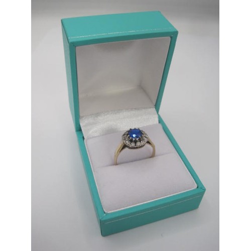 263 - A 9 carat gold dress ring set centrally with a round blue stone surrounded by twelve small white sto... 