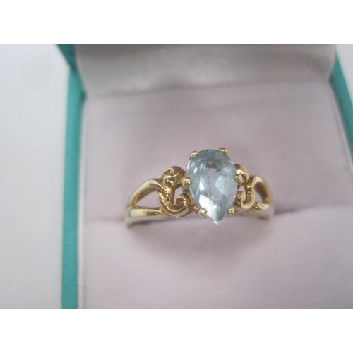 252 - A 9 carat gold ring set with a pear cut aquamarine in a pierced and scrolled shoulder setting. Ring ... 