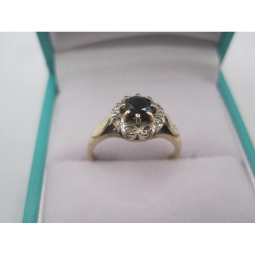 248 - A 9 carat ring set with a round sapphire in a claw setting with a halo of eight small diamonds, ring... 