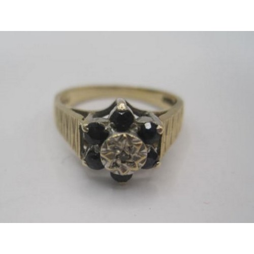 266 - A 9 carat gold sapphire and diamond ring. A foliate setting of six small round cut sapphires, centra... 