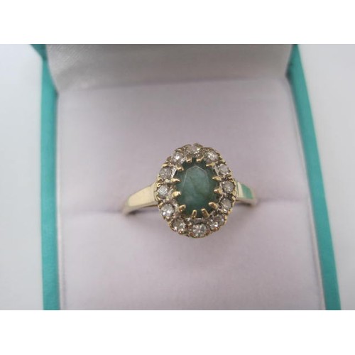 265 - A 9 carat gold emerald and diamond ring. The oval cut emerald (estimated at 5.5mm x 4.5mm) set in a ... 