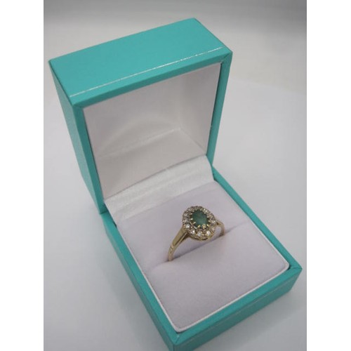 265 - A 9 carat gold emerald and diamond ring. The oval cut emerald (estimated at 5.5mm x 4.5mm) set in a ... 