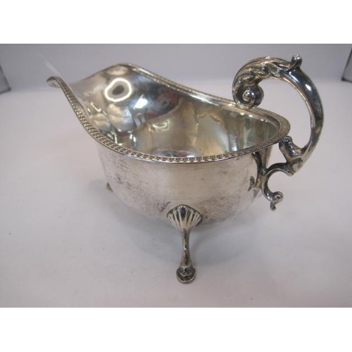 133 - Georgian style silver gravy boat with beaded rim, double scroll handle, on three hoof feet, partiall... 