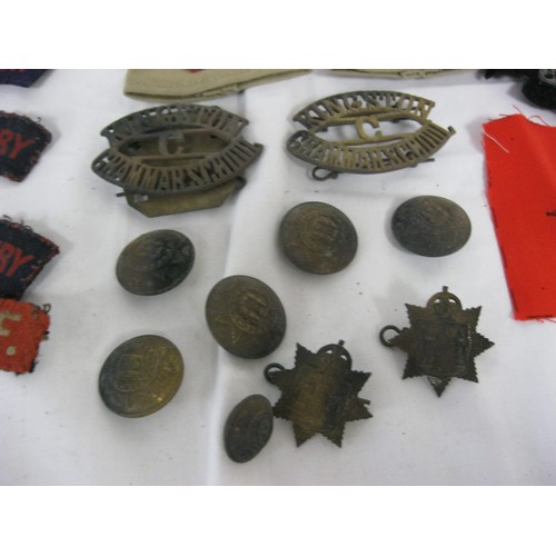 102 - A tin containing an assortment of military shoulder flashes, divisional badges and rank chevrons/sli... 