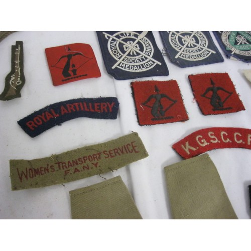 102 - A tin containing an assortment of military shoulder flashes, divisional badges and rank chevrons/sli... 