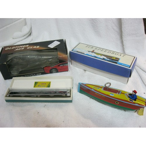 395 - A boxed tin plate speedboat, a boxed harmonica and a boxed model car in glass