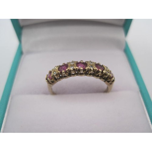 193 - A gold ruby and diamond dress ring. A row of five small rubies spaced by four pairs of very small di... 