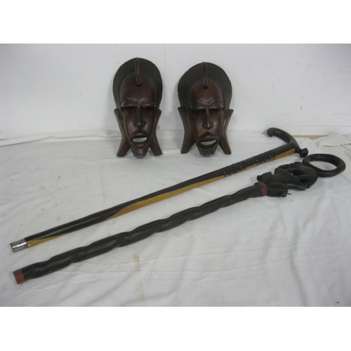 211 - A pair of carved African faces and a pair of Ethnic carved walking sticks