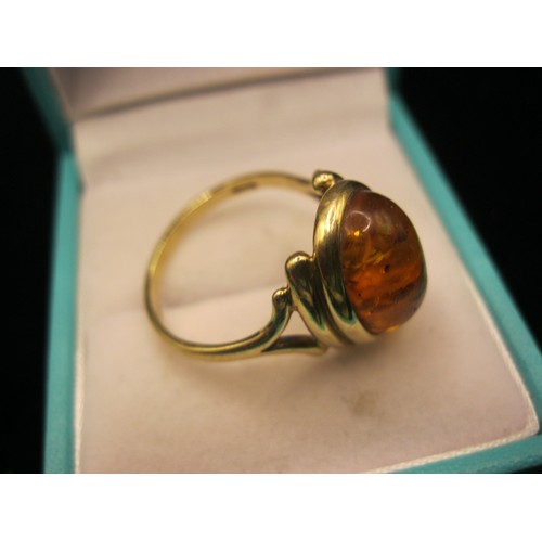 38 - A 9 carat imported gold ring set with an oval amber type stone. Ring size Q/R, gross weight approx. ... 