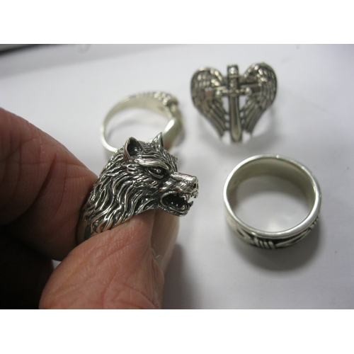 64 - 4 heavy silver gentleman's rings stamped for .925, one featuring a wolf's head, one angel's wings an... 