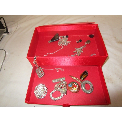 40A - A red jewellery box with a selection of costume jewellery including a stars and strips pin brooch.