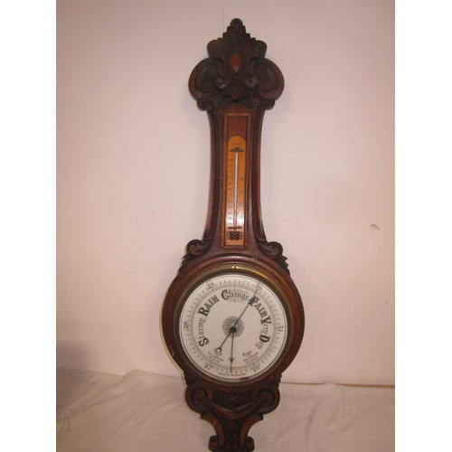 44 - An Aneroid Barometer mounted on a dark wood frame with Thermometer .