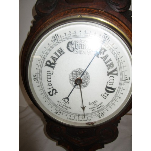 44 - An Aneroid Barometer mounted on a dark wood frame with Thermometer .