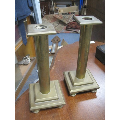 133 - A pair of industrial style candlesticks of heavy brass, each raised on spherical feet